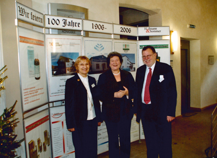 Dr. Ernst-Josef Strätling mit Ehefrau Elisabeth (links) und der damaligen Thüringer Landtagspräsidentin Dagmar Schipanski (CDU) beim  100-jährigen Firmenjubiläum von Hofmann & Sommer. ( 2 Frauen und ein Mann stehen vor einer Schautafel)