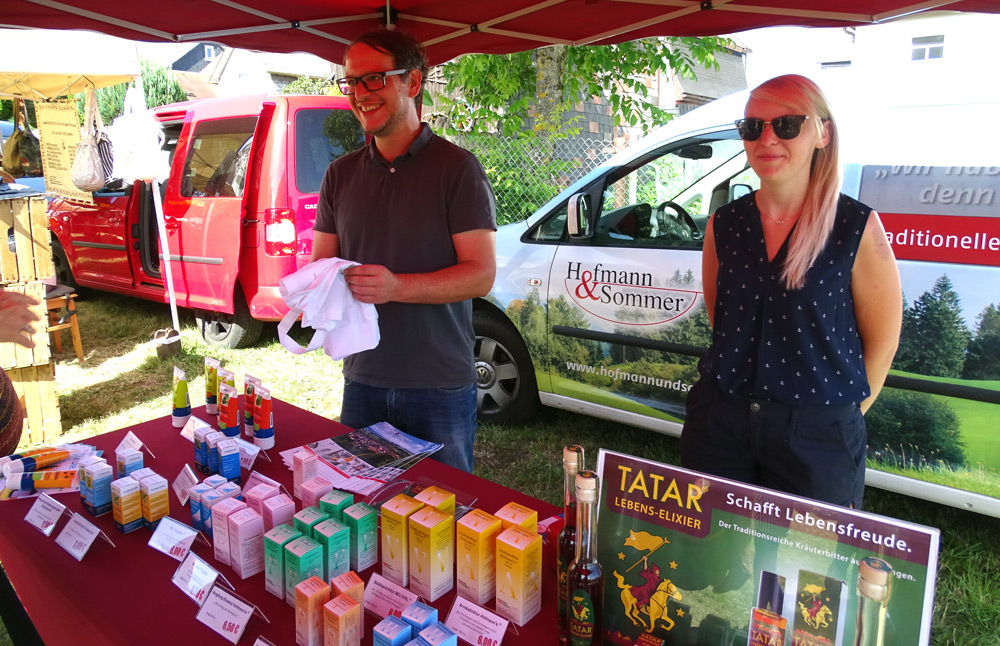 Zwei Personen an einem Stand auf einem Kräutermarkt.