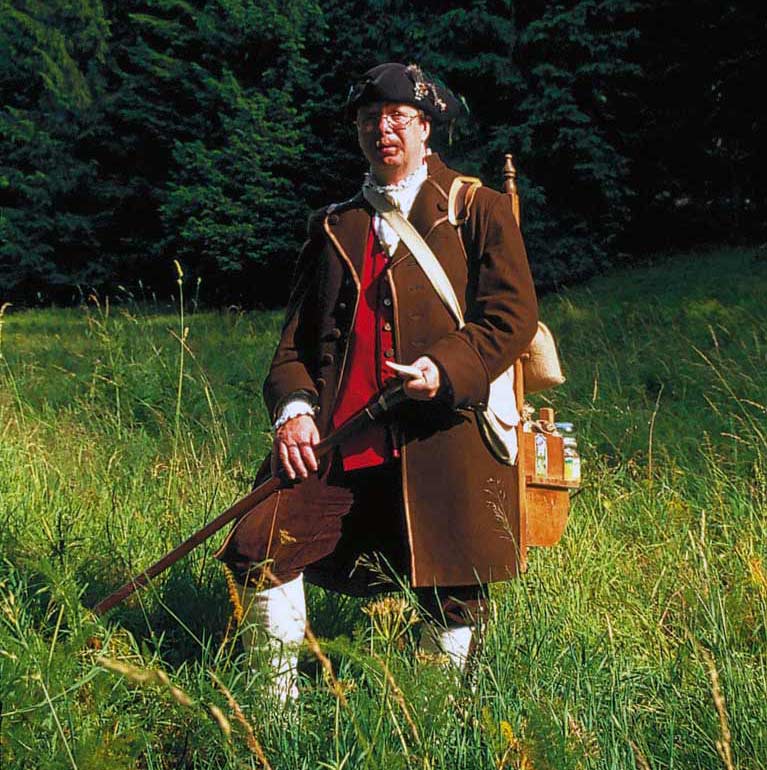 A man in the outfit of a humpback pharmacist in a meadow in the Thuringian Forest.